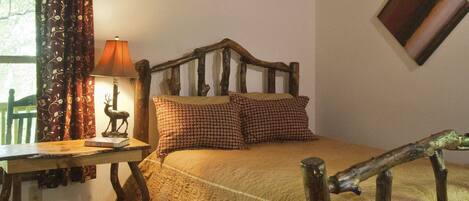A rustic bedroom with a wooden headboard, a desk with a lamp, and a deer figurine.