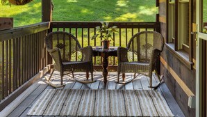 Eine hölzerne Veranda mit zwei Korbschaukeln, einem kleinen Tisch und Laternen.