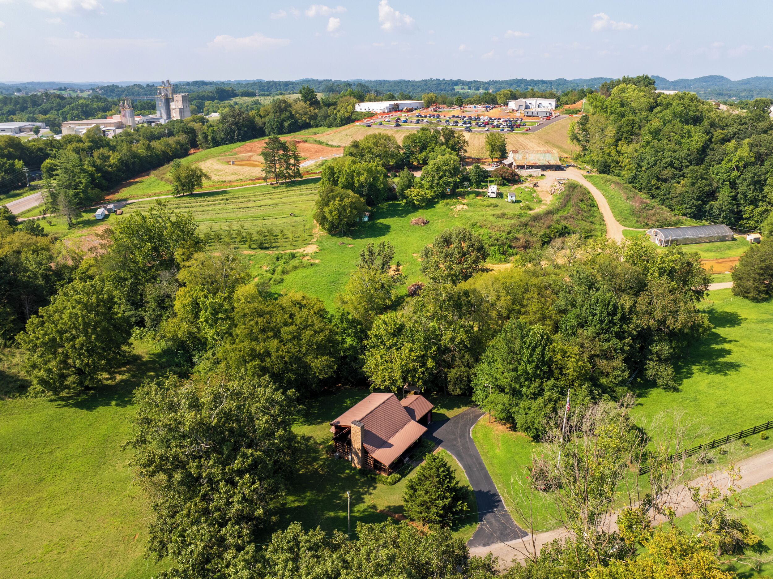 Vue aérienne d’une propriété rurale comprenant un grand champ, une ferme et un ensemble de panneaux solaires.
