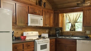 A kitchen with wooden cabinets, a white stove, a microwave, and a sink.