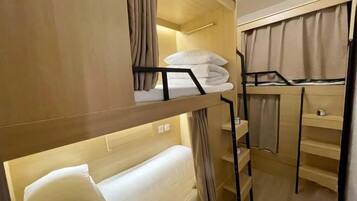 Quarto com beliche, escrivaninha e prateleiras.