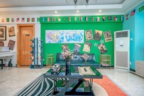 A reception area with a green wall, a black sofa, a coffee table, and a flag display. - Reverse Time Youth Hostel (Nanjing Station South Square Branch) (Nanjing)