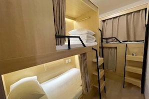 Habitación con literas, un escritorio y un pequeño estante.