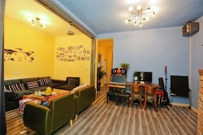 A living room with a sofa, coffee table, TV, and a guitar.