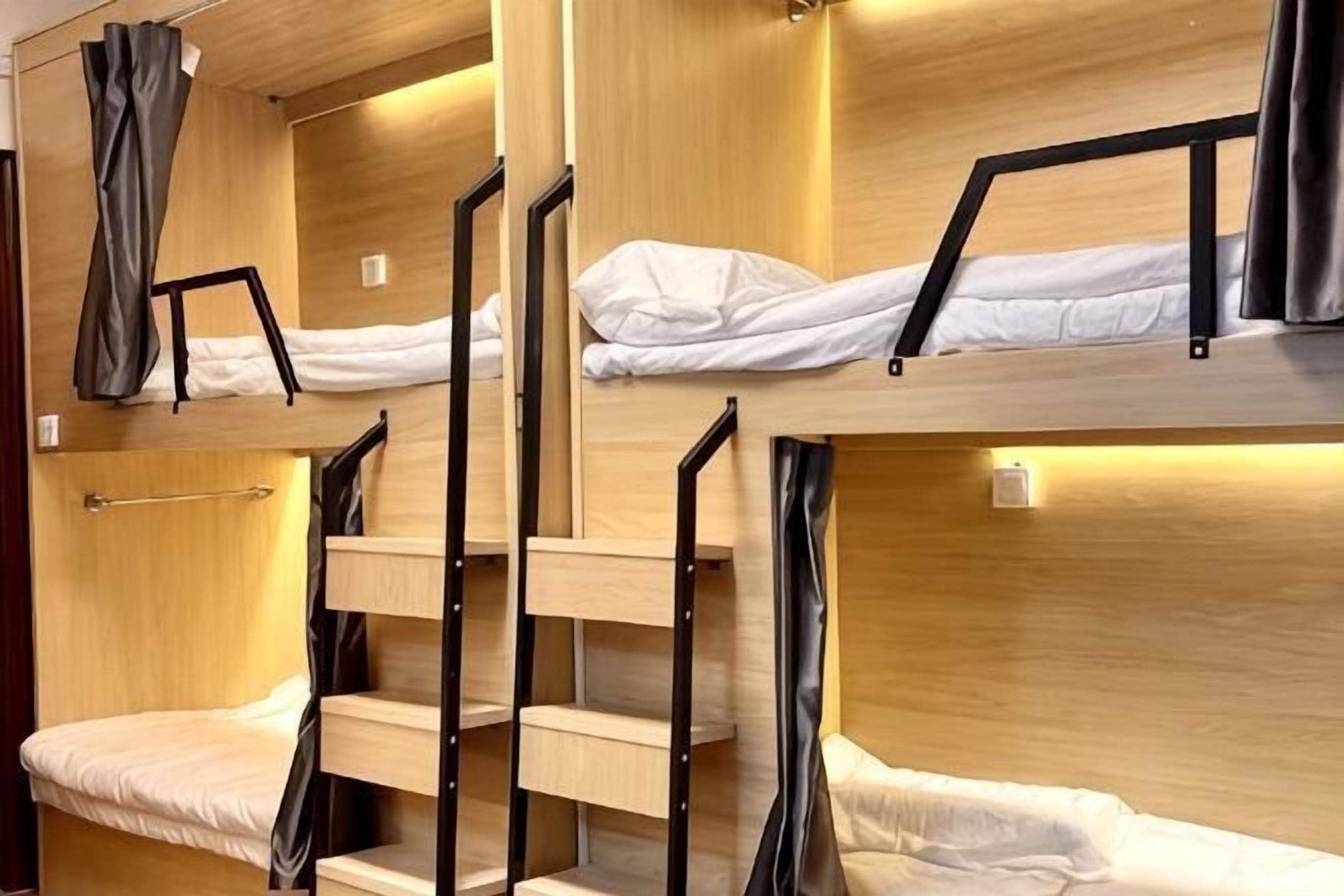 A bunk bed room with wooden walls, metal railings, and a small table.
