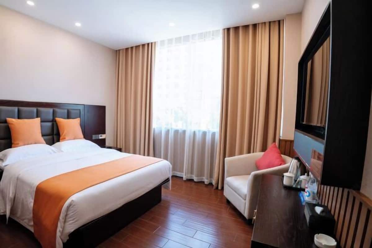Habitación de hotel con una cama grande, un escritorio, una silla y un televisor.
