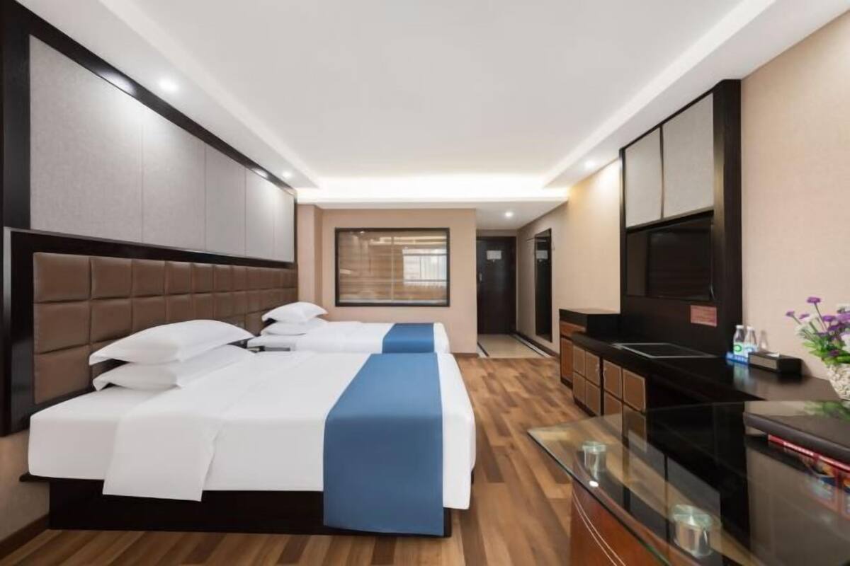 Habitación de hotel con una cama grande, televisión, minibar y un separador de vidrio.