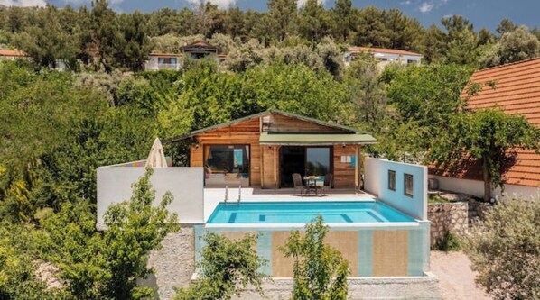 Escape to a serene retreat surrounded by lush greenery and overlooking a rectangular swimming pool.