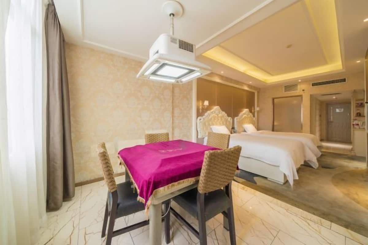 A hotel room with a dining area, a bed, a bathroom, and a view of the city.