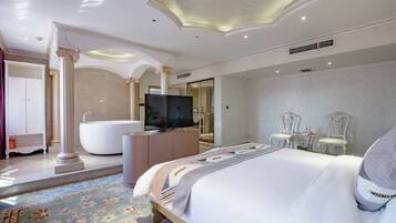 A spacious hotel room with a large bed, a bathtub, a television, and a seating area with chairs.