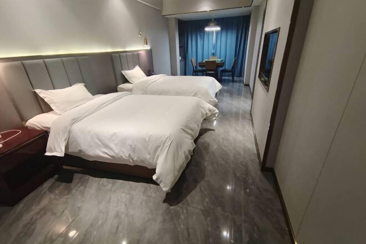 A hotel room with two beds, a desk, and a dining area with a table and chairs.
