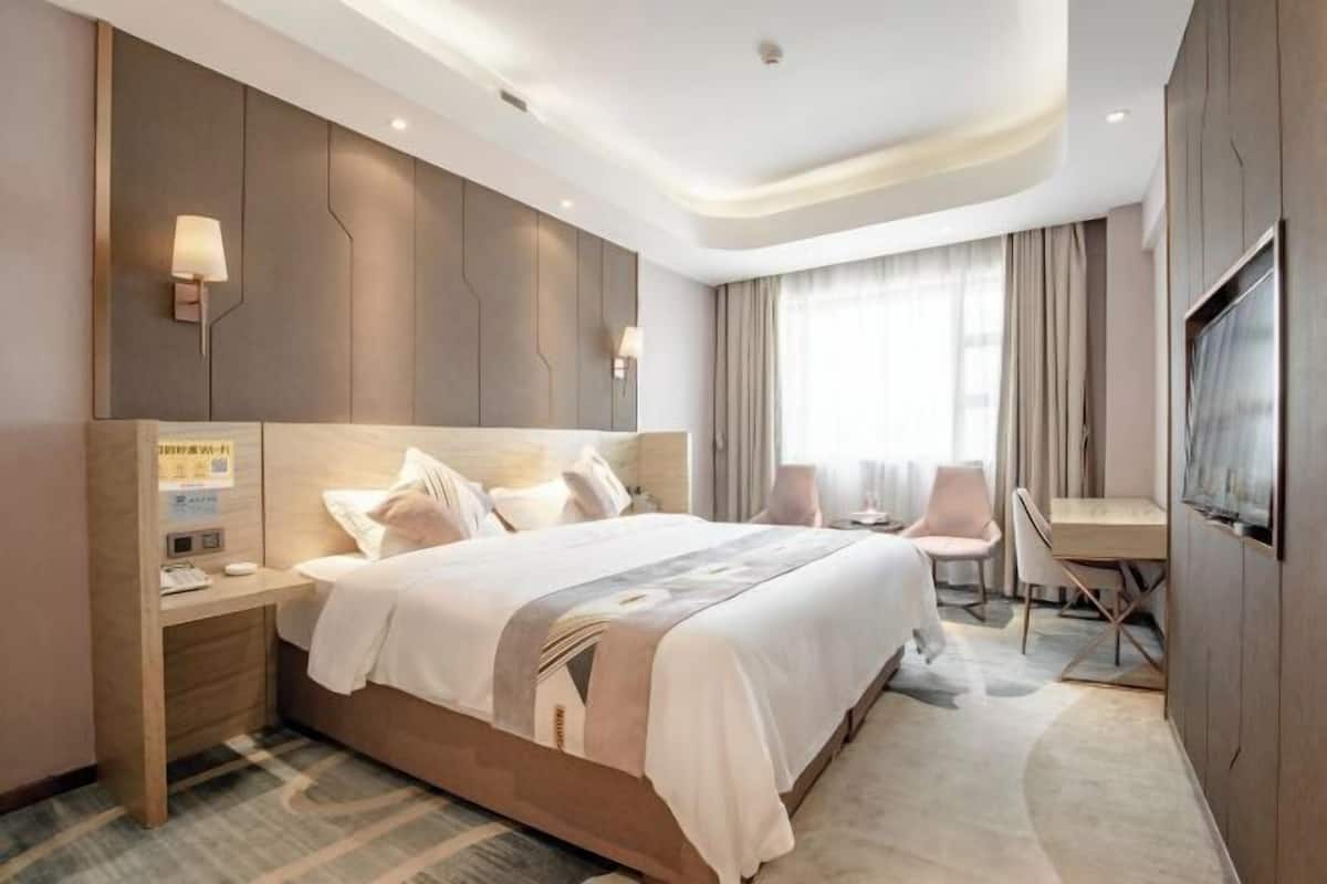 A modern hotel room with a large bed, bedside tables, a desk, and a TV.