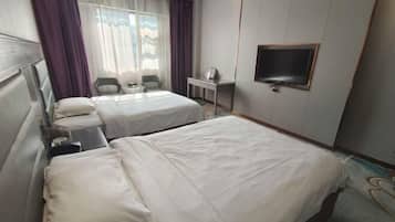 A hotel room with two beds, a desk, a chair, and a TV.
