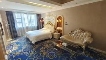 A hotel room with a large bed, a sofa, a glass coffee table, and a decorative mirror.