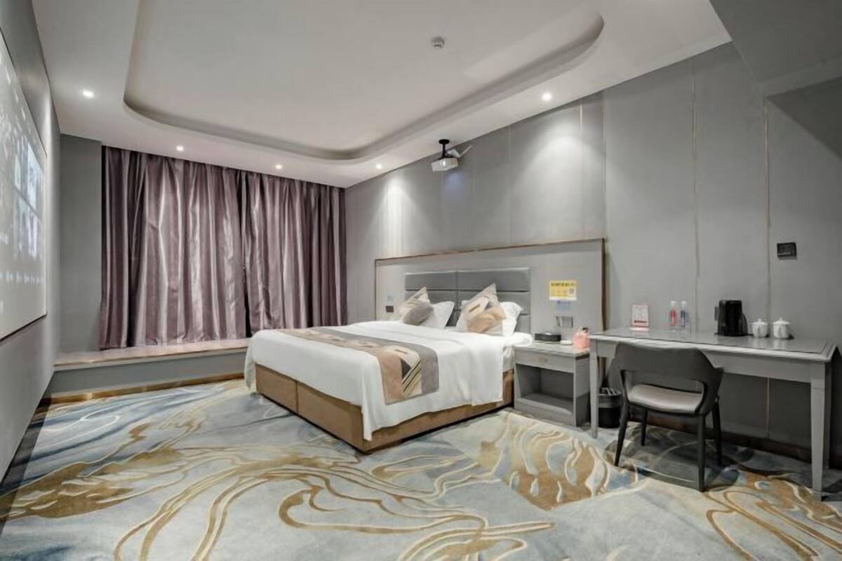 A modern hotel room with a large bed, a desk, and a chair.