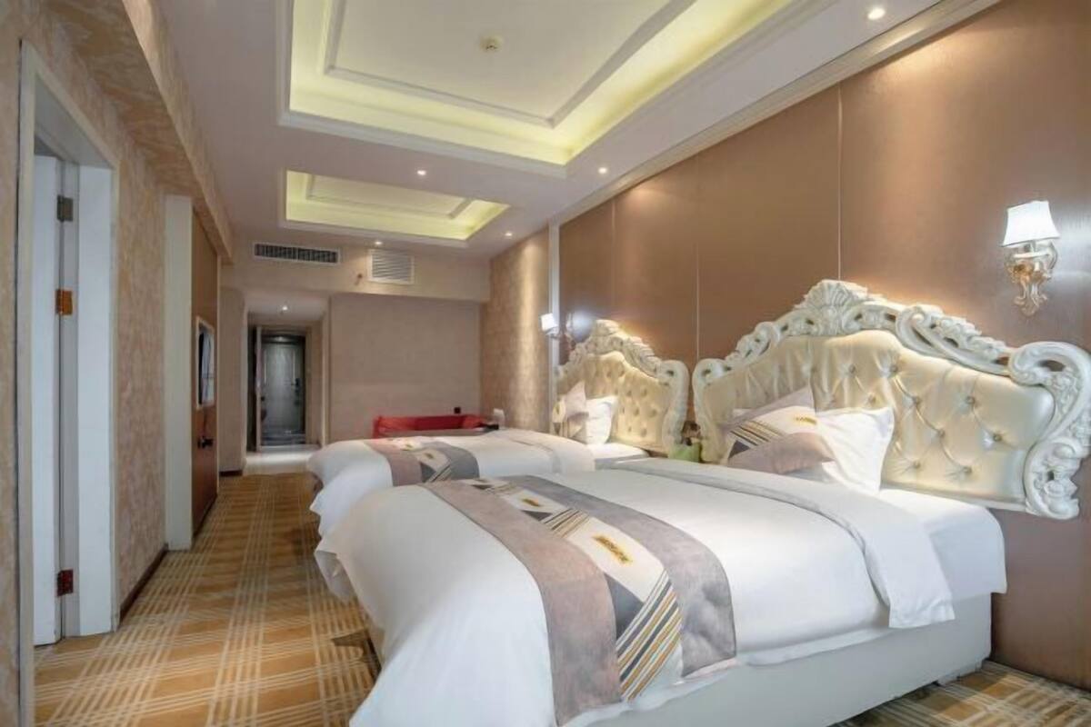 A hotel room with two beds, a hallway, and a door leading to another room.