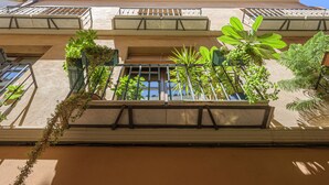 A multi-story building with balconies, large windows, and potted plants. - Solaga - Pozos Dulces (Málaga)