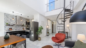 A modern interior with a dining area, kitchen, living room, and a spiral staircase. - Solaga - Pozos Dulces (Málaga)