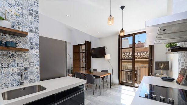 A modern kitchen with a large island, built-in appliances, and a dining area with a table and chairs. - Solaga - Pozos Dulces (Málaga)