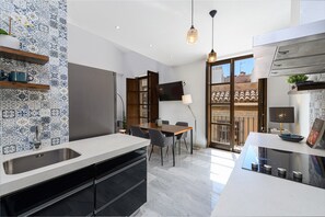 A modern kitchen with a large island, built-in appliances, and a dining area with a table and chairs. - Solaga - Pozos Dulces (Málaga)