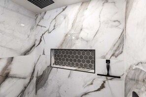 A bathroom with a marble wall, a hexagonal tile backsplash, and a black faucet.