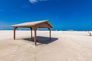 Une plage avec une structure en bois, peut-être un kiosque, et un ciel bleu dégagé.