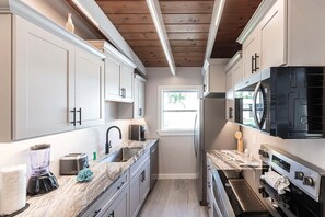 A modern kitchen with white cabinets, a granite countertop, a built-in oven, and a window providing natural light.