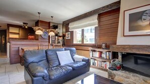 A cozy living room with a leather sofa, a fireplace, and a bookshelf. - Meters from the lift station with a private terrace and balcony in Verbier (Val de Bagnes)