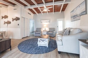 A spacious living room with a high ceiling, a fireplace, and a view of the outdoors.