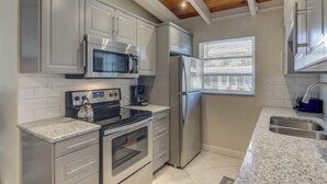 Una cucina moderna con elettrodomestici in acciaio inossidabile, mobili bianchi e soffitto in legno.