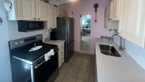 A kitchen with a microwave, oven, refrigerator, and a sink.