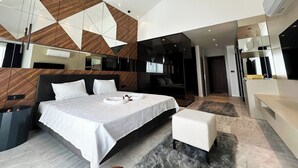 A modern bedroom with a large bed, a small seating area, and a walk-in closet. - Villa Sun 10 - PLANET LUXURY VILLAS (Kas)