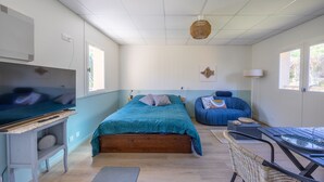 A bedroom with a bed, a desk, a chair, a blue sofa, and a window. - Marée Basse - Studio proche plage de la potinière (Barneville-Carteret)