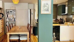 Une cuisine moderne dotée d’un îlot central, d’un coin repas avec une table et des chaises en bois, et d’une bibliothèque remplie de livres.