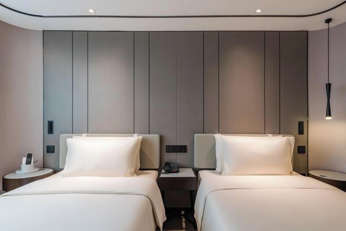 Ein Hotelzimmer mit zwei Betten, einem Nachttisch mit Telefon und einer Wandleuchte.