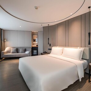 Une chambre moderne avec un grand lit, un canapé, une table de chevet et une étagère fixée au mur.