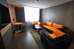 A modern hotel room with a sofa, a small table, a chair, and a television. - Atour S Hotel Wenshu Yuan MonasterySubway Station, Chunxi Road (Chengdu)