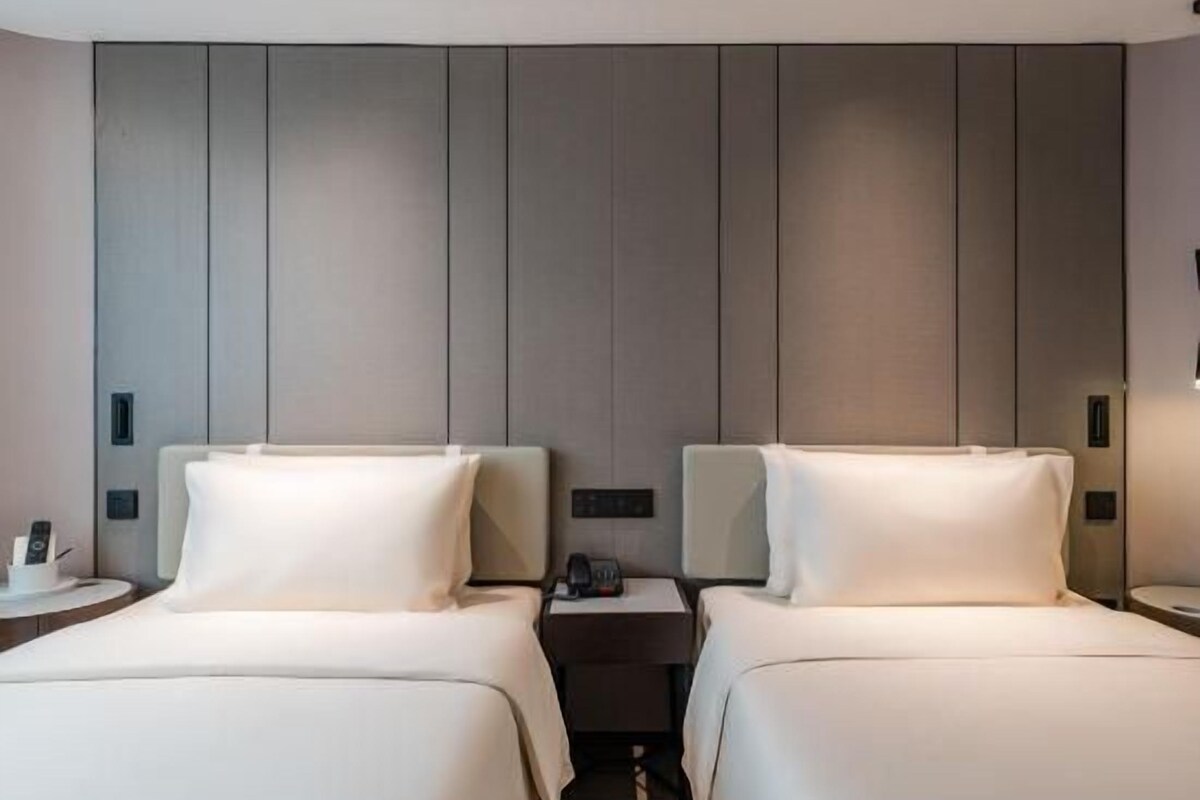 Ein Hotelzimmer mit zwei Betten, einem Nachttisch mit Telefon und einer Wandleuchte.