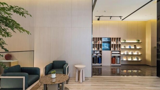Una hall moderna con un'area salotto, un tavolino da caffè e una libreria con libri e oggetti decorativi.