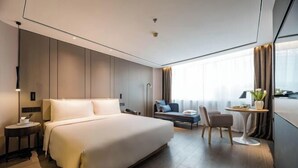 Camera d'albergo moderna con un letto grande, una scrivania, una sedia e vista sulla città.
