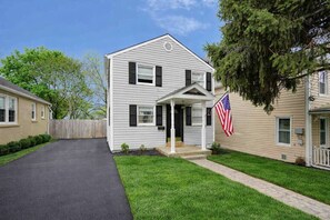 A two-story house with a front porch, a driveway, and a well-maintained lawn. - Historic Downtown Home with Fire Pit (Leesburg)