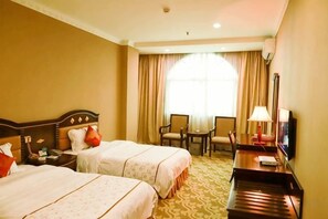 Une chambre d’hôtel avec deux lits, un bureau avec une lampe, une télévision et une chaise.