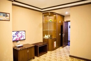 Een hotelkamer met een televisie, een houten kastje en een inloopkast met planken.