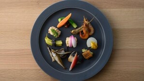 Une assiette ronde, sur laquelle sont disposés divers fruits de mer et légumes, est posée sur une table en bois.