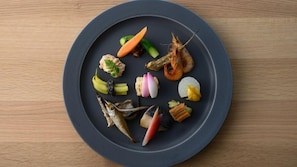 Un plato redondo con diversos mariscos y verduras sobre una mesa de madera.