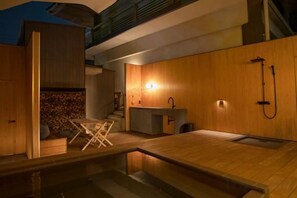 A modern bathroom with a wooden vanity, a shower, and a small seating area. - ANABUKI-TEI (Takamatsu)