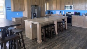 Eine moderne Küche mit Holzschränken, einer zentralen Kochinsel mit Barhocker, Edelstahlgeräten und einer blauen Akzentwand.