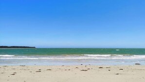 Uma praia com céu claro e águas calmas.