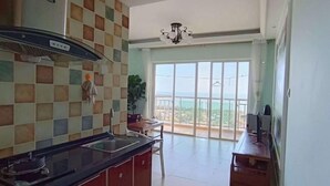 Cozinha com painel de azulejos xadrez, sala de jantar com mesa e cadeiras, e varanda com vista.