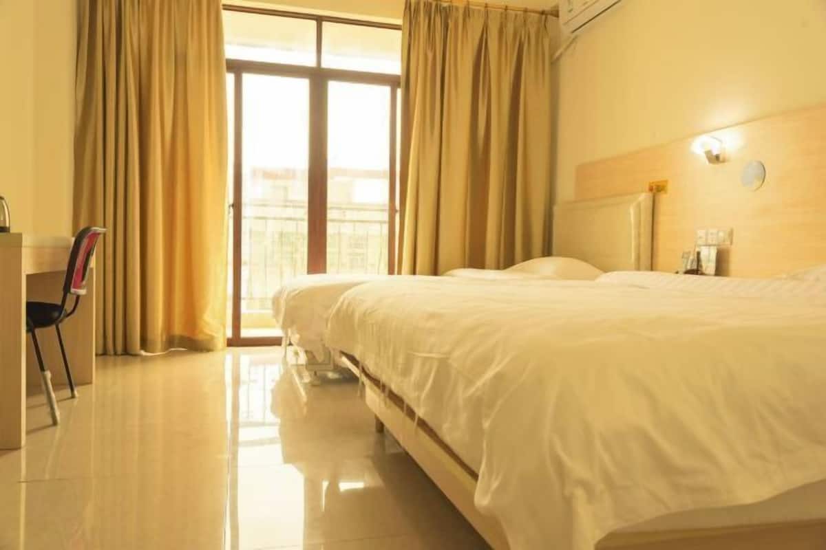 Una habitación de hotel con una cama grande, un escritorio y vistas a través de una puerta de cristal.